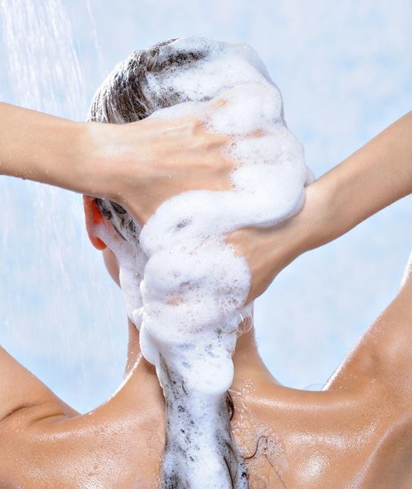 washing long brunette female hair by shampoo - close-up