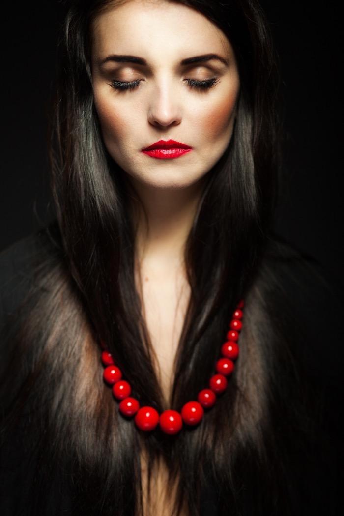 Beautiful glamour woman with dark shiny hair, long eyelashes and red beads