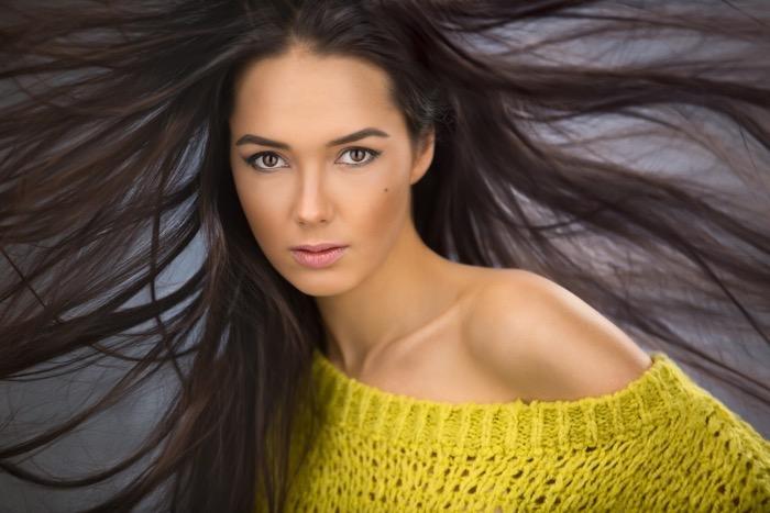 Portrait of a charming sexy brunette with long flowing hair wind. The picture was taken in a photo studio with a wind machine.